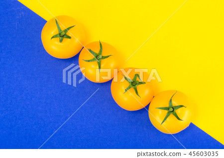 Bright yellow and red tomatoes on colored background 45603035
