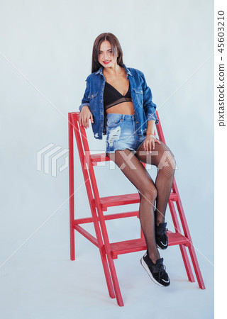 Fashionable brunette beautiful woman posing in studio wearing short jeans. 45603210