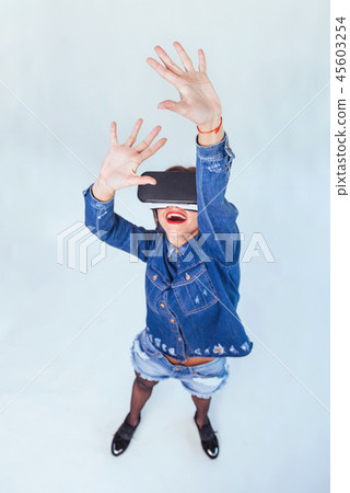 brunette beautiful woman posing in the studio, wearing jeans wear, using VR-glasses virtual reality brunette beautiful woman posing in the studio, wearing jeans wear, using VR-glasses virtual reality 45603254