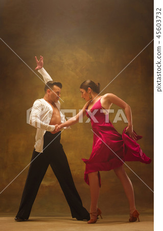 Dance ballroom couple in gold dress dancing on studio background. Dance ballroom couple in gold dress dancing on studio background. 45603732