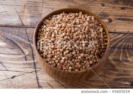 Buckwheat raw in a wooden bowl on a rustic wooden  45605639