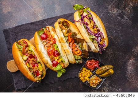 Hot dogs with assorted toppings on a dark 45605849