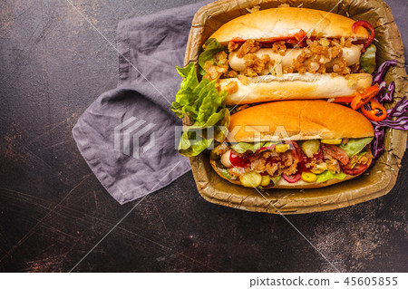 Hot dogs with assorted toppings on a dark 45605855