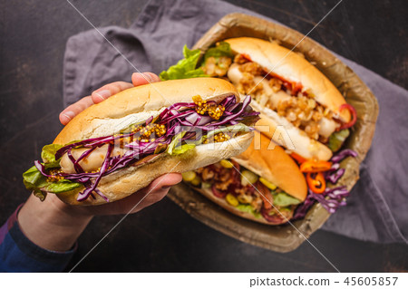 Hot dogs with assorted toppings on a dark 45605857