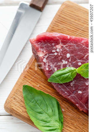 Raw meat with marinated salt, pepper and Basil seasoning leaf. Morning in the kitchen. Raw fresh 45607207