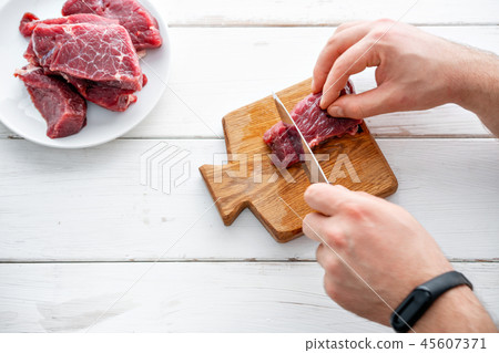 Closeup of the hands of a butcher cutting slices of raw meat off a large loin. Raw meat. Raw fresh 45607371