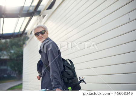 Image of young woman with green bike against gray wall Image of young woman with green bike against gray wall 45608349