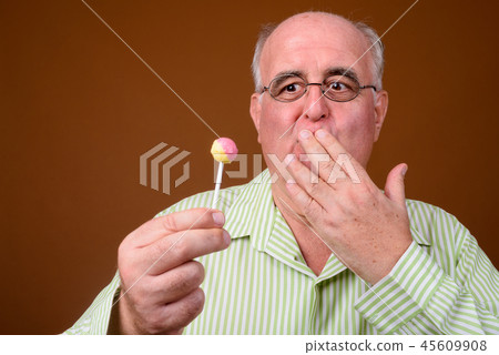 Overweight senior man wearing eyeglasses against brown backgroun Overweight senior man wearing eyeglasses against brown backgroun 45609908