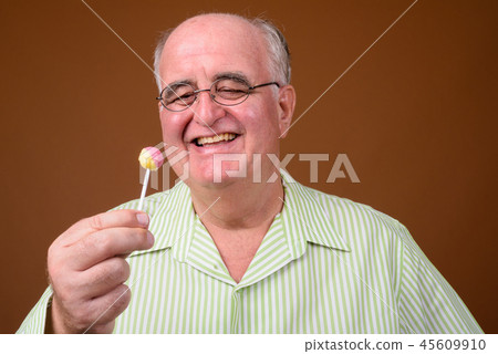 Overweight senior man wearing eyeglasses against brown backgroun Overweight senior man wearing eyeglasses against brown backgroun 45609910