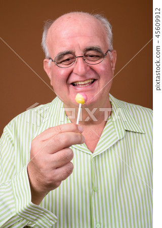 Overweight senior man wearing eyeglasses against brown backgroun Overweight senior man wearing eyeglasses against brown backgroun 45609912