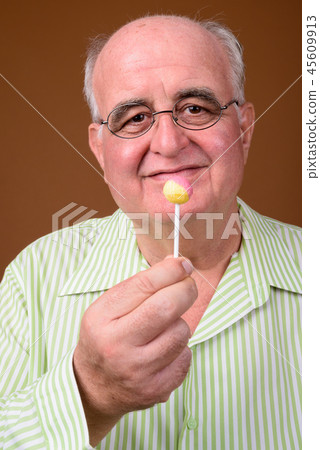 Overweight senior man wearing eyeglasses against brown backgroun Overweight senior man wearing eyeglasses against brown backgroun 45609913