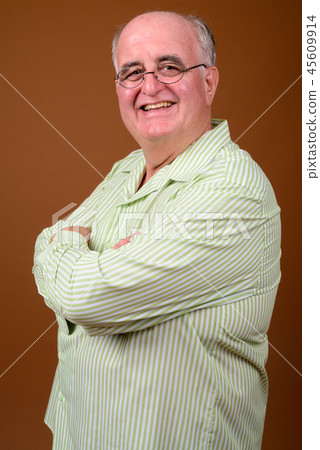 Overweight senior man wearing eyeglasses against brown backgroun Overweight senior man wearing eyeglasses against brown backgroun 45609914