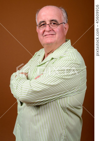Overweight senior man wearing eyeglasses against brown backgroun Overweight senior man wearing eyeglasses against brown backgroun 45609916