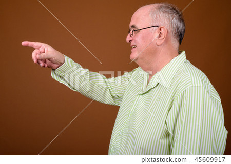 Overweight senior man wearing eyeglasses against brown backgroun 45609917