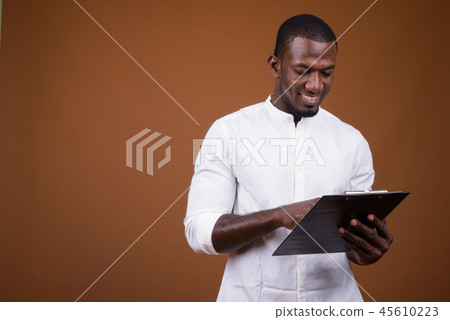 Portrait of handsome African businessman against brown background Portrait of handsome African businessman against brown background 45610223