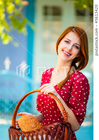 girl in red dress with basket near old blue color house girl in red dress with basket near old blue color house 45613420