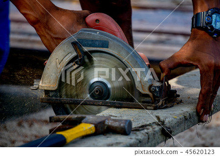 Man use electrical portable circular saw cuts log Man use electrical portable circular saw cuts log 45620123