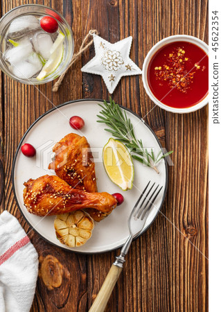 Tasty appetizing baked chicken legs served with spices, rosemary and cranberries on wooden 45622354