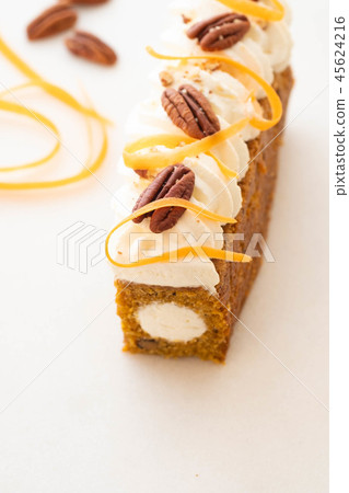 Carrot cake pie, sprinkled with nuts, decorated with cream-colored carrots on white marble. 45624216