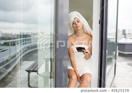 Beautiful woman with the white towel on her head does makeup . 45625379