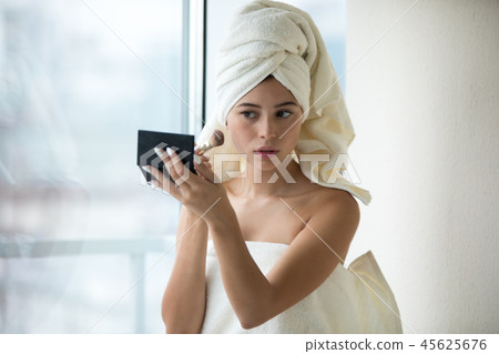 Beautiful woman with the white towel on her head does makeup . Beautiful woman with the white towel on her head does makeup . 45625676