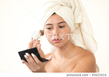 Beautiful woman with the white towel on her head does makeup . Beautiful woman with the white towel on her head does makeup . 45625818