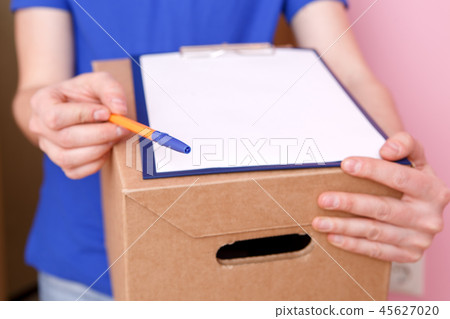 Photo close up of courier with pen, blank sheet of paper, cardboard box 45627020