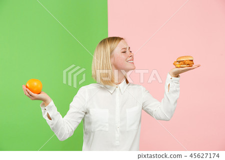 Diet. Dieting concept. Healthy Food. Beautiful Young Woman choosing between fruits and unhelathy 45627174