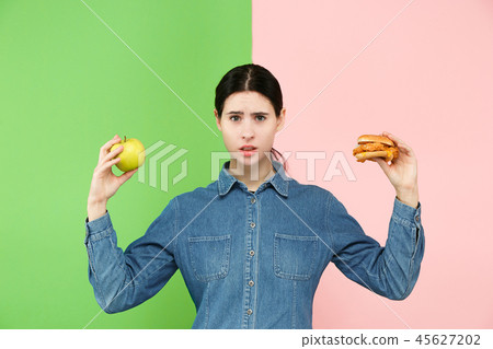 Diet. Dieting concept. Healthy Food. Beautiful Young Woman choosing between fruits and unhelathy Diet. Dieting concept. Healthy Food. Beautiful Young Woman choosing between fruits and unhelathy 45627202