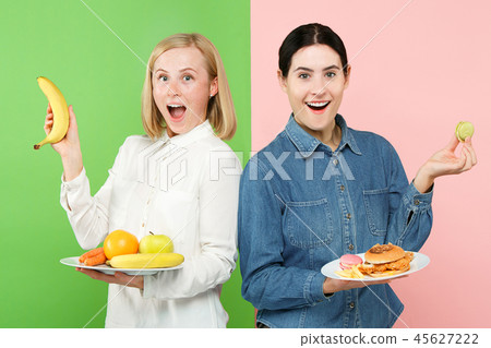 Diet. Dieting concept. Healthy Food. Beautiful Young Women choosing between fruits and unhelathy Diet. Dieting concept. Healthy Food. Beautiful Young Women choosing between fruits and unhelathy 45627222