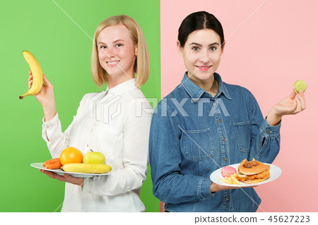 Diet. Dieting concept. Healthy Food. Beautiful Young Women choosing between fruits and unhelathy 45627223