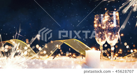Two glasses filled with garlands with a candle and a gold ribbon in the snow Two glasses filled with garlands with a candle and a gold ribbon in the snow 45628707