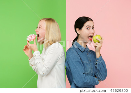 Diet. Dieting concept. Healthy Food. Beautiful Young Women choosing between fruits and unhelathy 45629800
