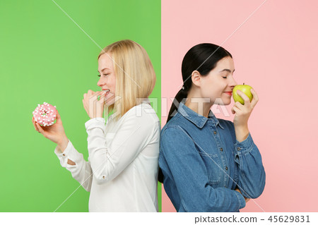 Diet. Dieting concept. Healthy Food. Beautiful Young Women choosing between fruits and unhelathy 45629831
