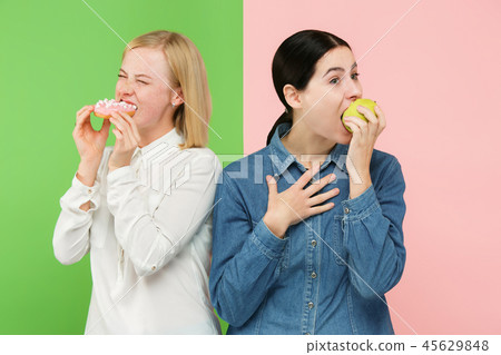Diet. Dieting concept. Healthy Food. Beautiful Young Women choosing between fruits and unhelathy 45629848