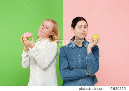 Diet. Dieting concept. Healthy Food. Beautiful Young Women choosing between fruits and unhelathy 45629853