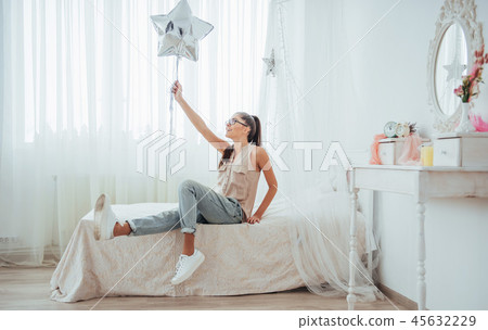 Closeup cute brunette girl in the studio, smiling broadly and playing with transparent and silver 45632229