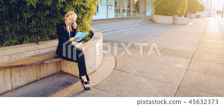 Secretary talking by smartphone with document case in   outdoors 45632373