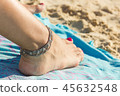 Ankle bracelet on foot with nail polished on beach 45632548