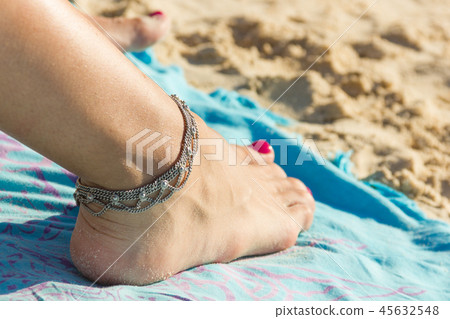 Ankle bracelet on foot with nail polished on beach Ankle bracelet on foot with nail polished on beach 45632548