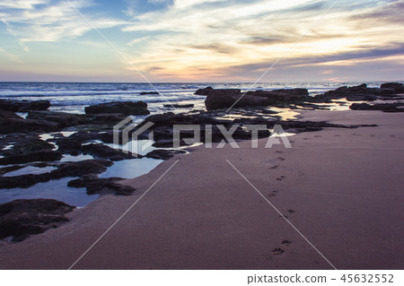 Dog track on sand by rocky shore at great sunset Dog track on sand by rocky shore at great sunset 45632552