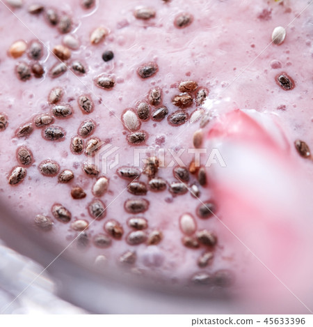 Macro photo appetizing milky berry smoothie with organic chia seeds in a glass with a straw. Healthy Macro photo appetizing milky berry smoothie with organic chia seeds in a glass with a straw. Healthy 45633396