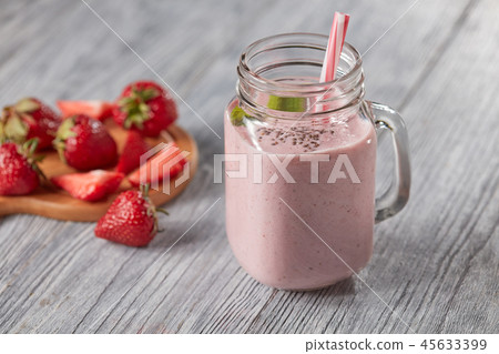 Healthy milk drink with strawberries, chia seeds and fresh mint leaves in a jar with a straw on a Healthy milk drink with strawberries, chia seeds and fresh mint leaves in a jar with a straw on a 45633399