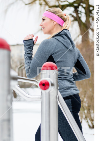 Young woman training her legs on fitness path in winter Young woman training her legs on fitness path in winter 45634211