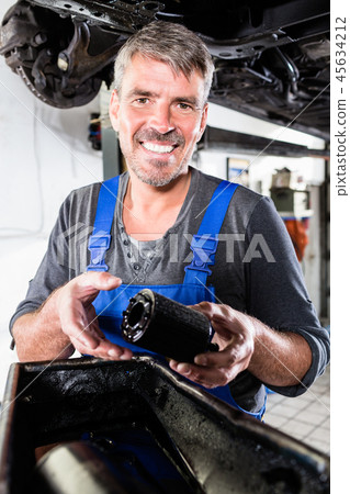 Smiling mature man holding the oil filter of a car 45634212
