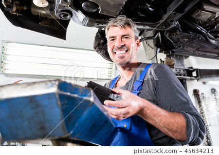 Mature mechanic holding a vehicle part 45634213