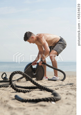 Man with ropes on a beach in a daylight Man with ropes on a beach in a daylight 45634639