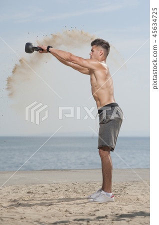 Man with a naked body doing kettlebell exercise 45634725
