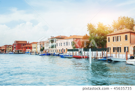 Green water channel with gondolas and colorful facades of old medieval buildings in the sun in Green water channel with gondolas and colorful facades of old medieval buildings in the sun in 45635735