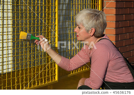 Worker painting metal protective net to yellow color 45636176